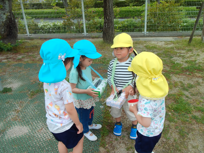 3，4歳児が四人で、箱に入れたダンゴムシを見ている
