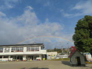 幼稚園舎の上に虹がかかっている