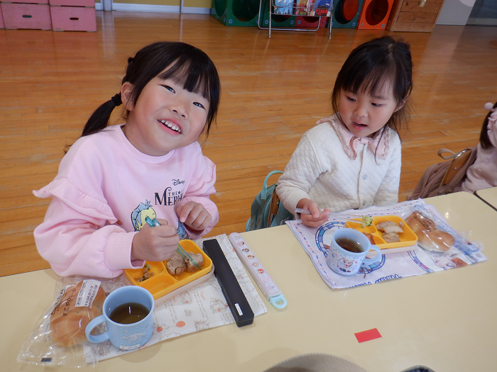 宅配弁当を友達とおいしそうに食べてにっこり笑っている4歳児