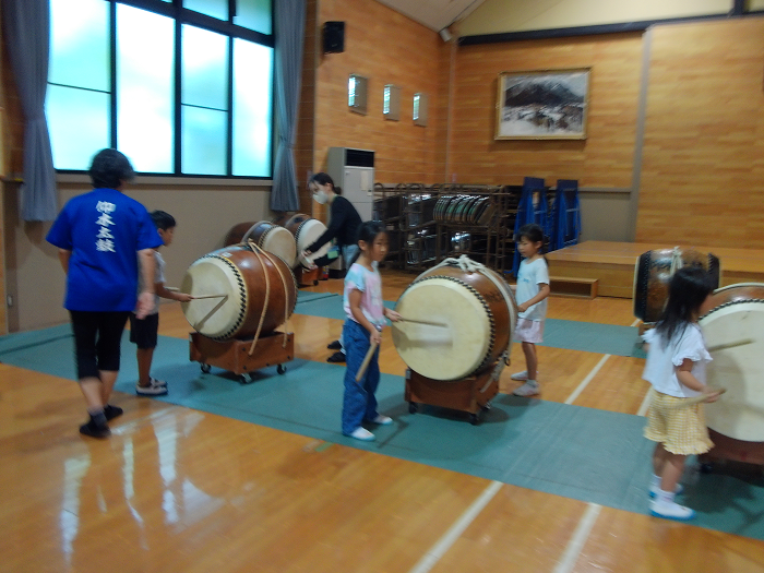 大きな寸胴太鼓をたたいている5歳児