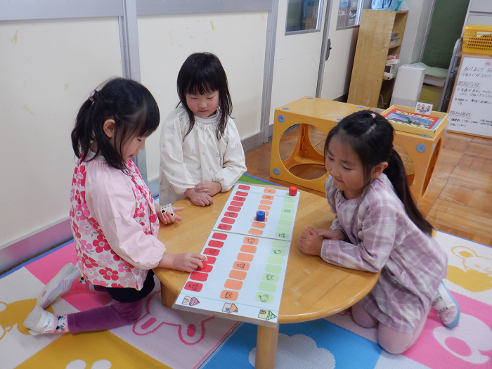 4歳児女児三人が座卓を囲み双六をしている