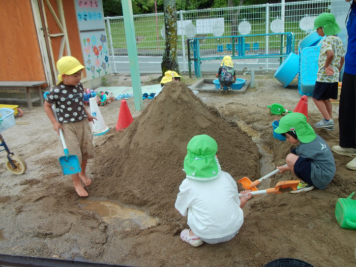 砂場で大きな山をつくっている4歳児