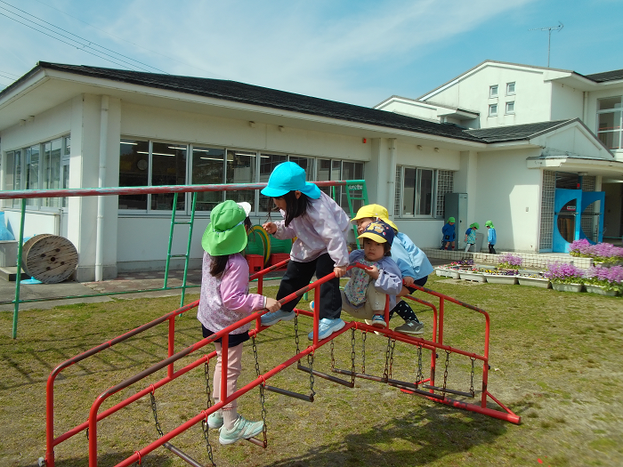 揺れる梯子の遊具に4人の子どもが乗っている