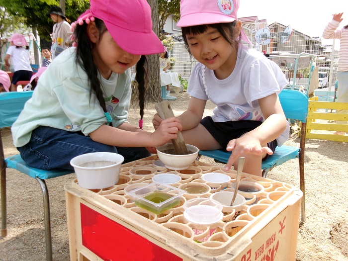 2人の子どもが同じ入れ物を使って色水をつくっている様子