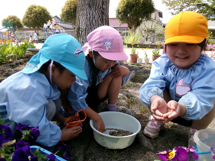 3人の子どもがダンゴムシ探しをしている様子