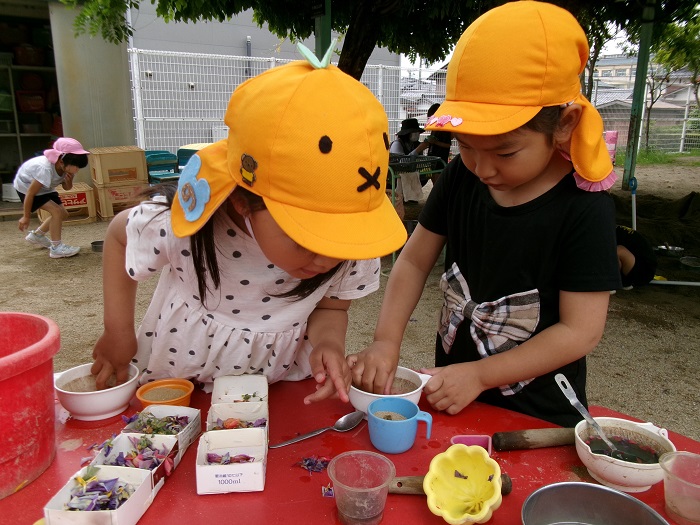 花びらを手ですりつぶして色水をつくっている様子