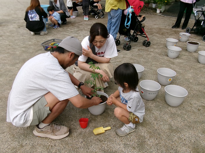 親子で植木鉢にプチトマトを植えている様子