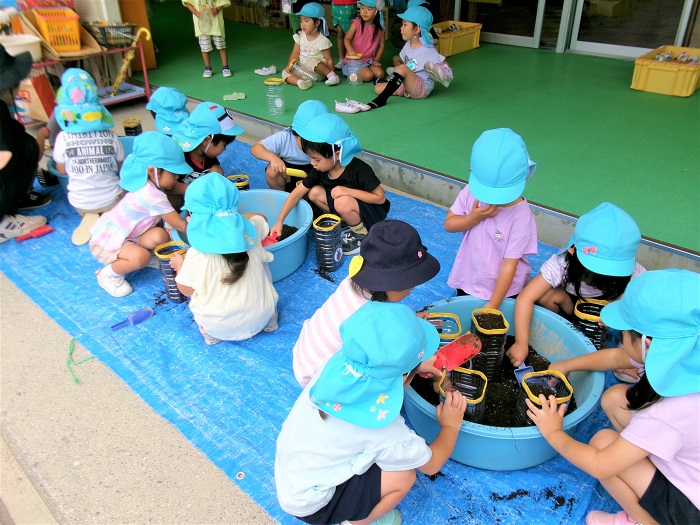 子どもたちがペットボトル植木鉢に土を入れているところ