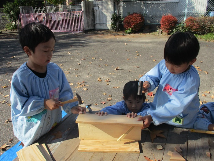 子どもたちがかなづちを使って木工遊びをしている様子