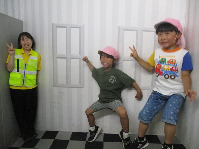 トリックアートの部屋で遊ぶ先生と子どもたちの様子