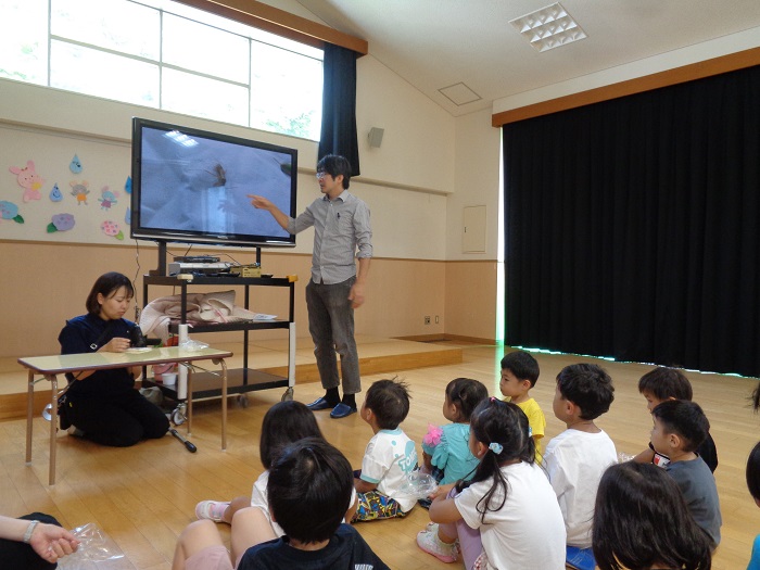 捕まえた虫をテレビで大きく映して見る子どもたち