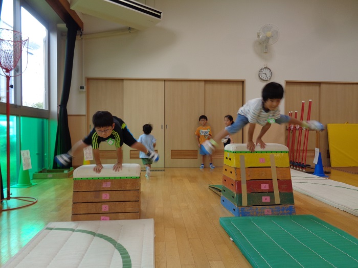友達とタイミングを合わせて一緒に跳び箱を飛ぶ5歳児