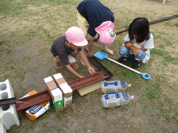 5歳児がトイをつなげて水を流そうと友達と考えている様子