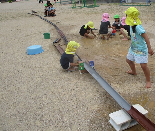 トイをつなげて水を流す遊びを楽しむ子どもたちの様子
