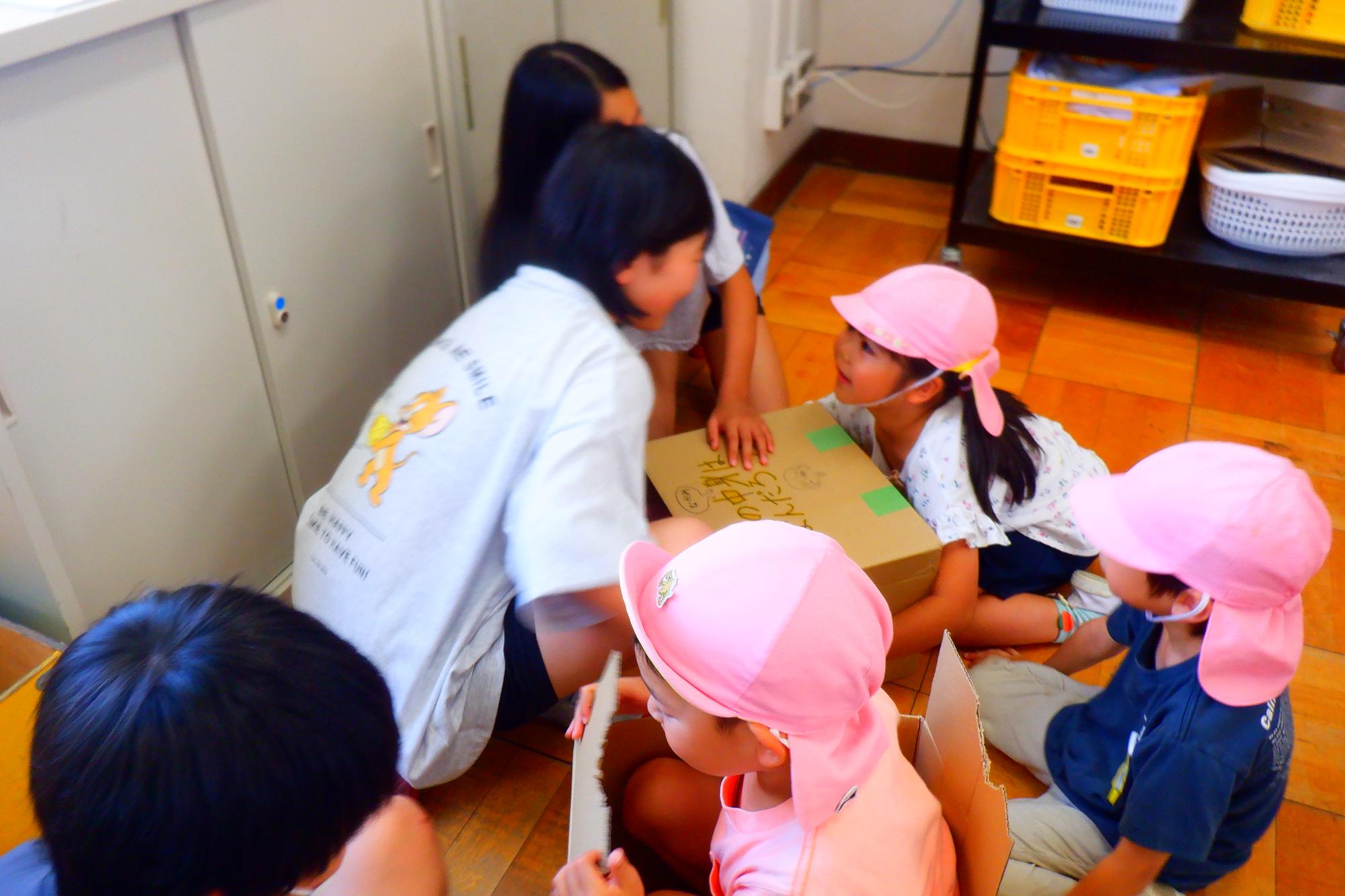 5年生と5歳児が箱を使って遊んでいるところ