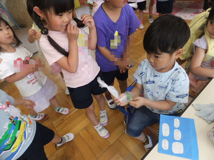 5歳児と4歳児　　5歳児が育てスナップエンドウを4歳児におすそわけしているところ
