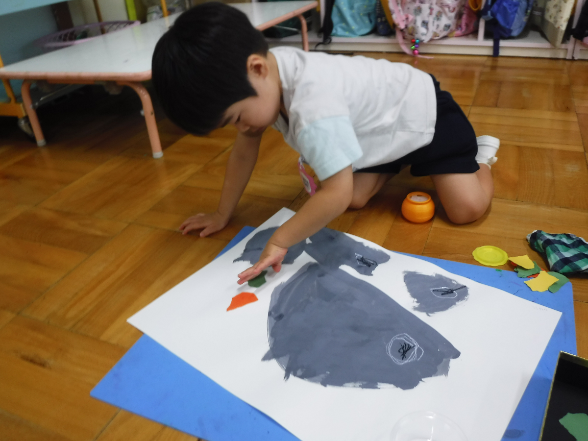 子どもがダンゴムシの絵をかいて葉っぱを貼り付けているところ