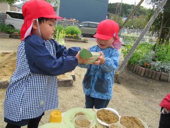 砂でごちそうをつくって遊ぶ3歳児