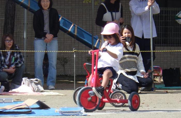 運動遊びで三輪車に乗る4歳児