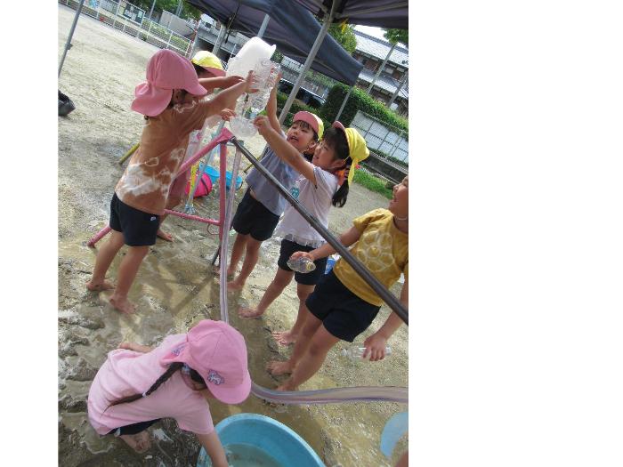 ホースの水がどうやったら流れるか試しながら遊ぶ4・5歳児
