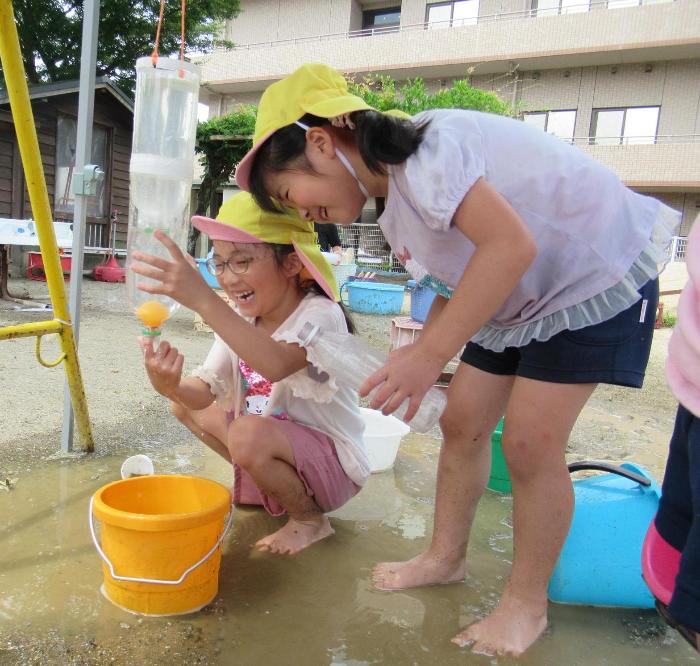 ピン給を押すとたまっている水が流れだす仕掛けを楽しんでいる5歳児