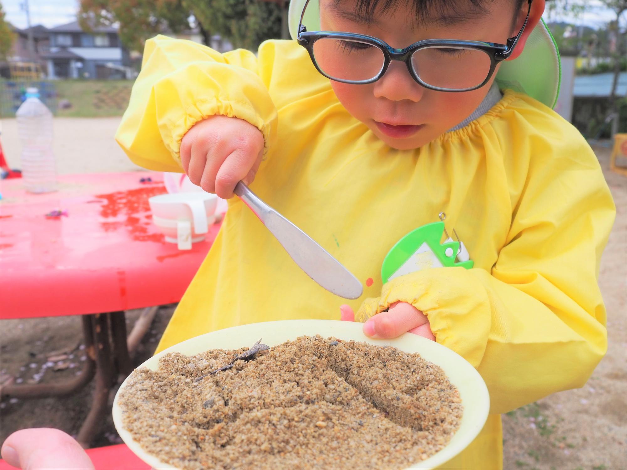 子どもが砂でごちそうを作っている様子