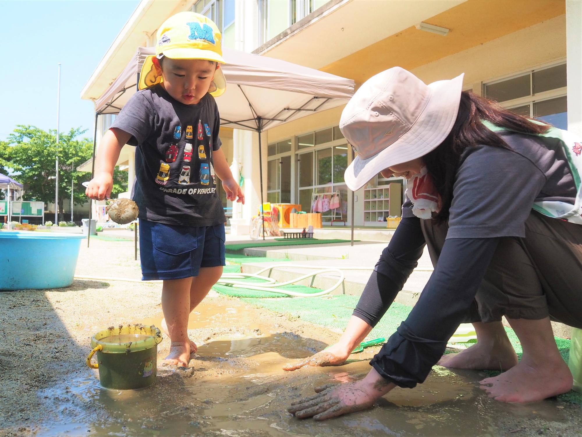 砂場に裸足で足を踏み入れている子ども