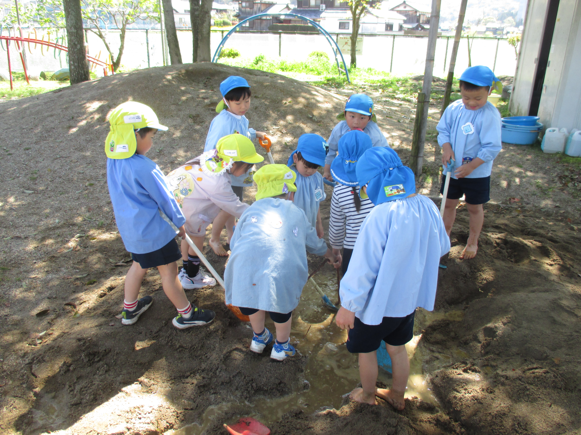砂場で池つくりをする4・5歳児