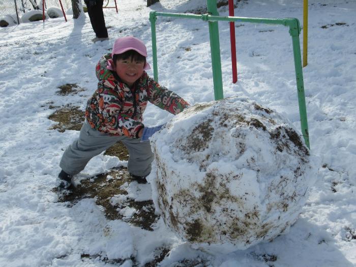 大きな雪だるまを作っている3歳児