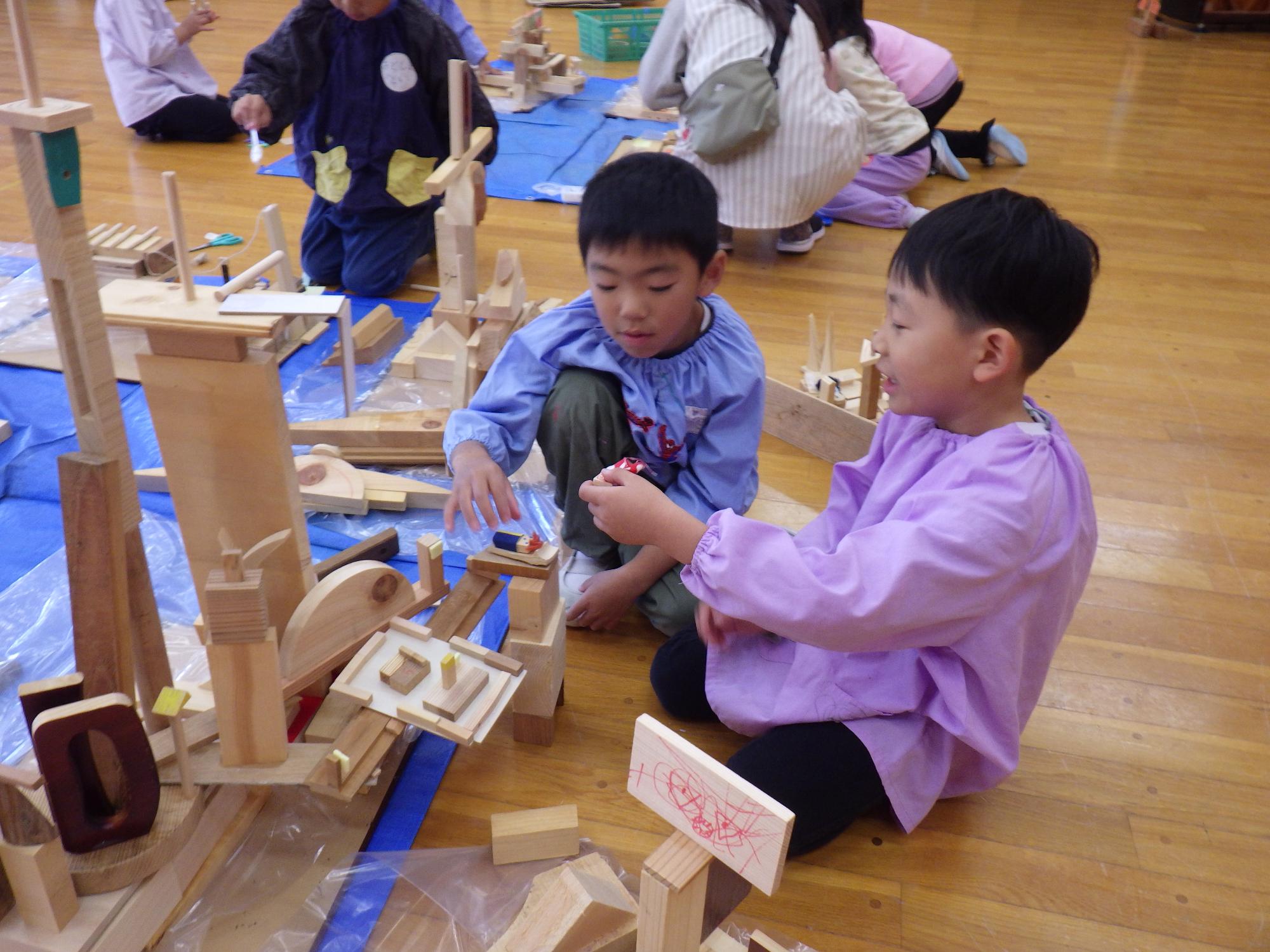 こどもたちが木片でお家や船をつくって遊んでいる様子