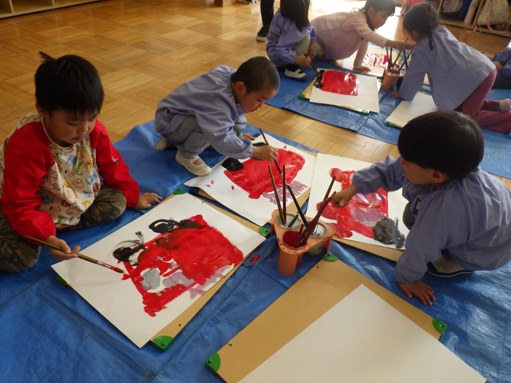 子ども達が絵の具で消防車を書いている様子