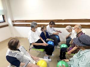 介護職員が利用者にボールで体操を教えている写真