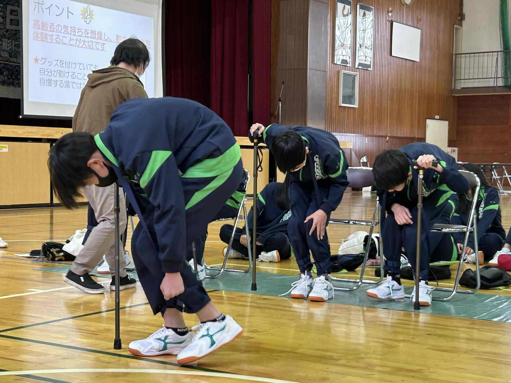 高齢者の疑似体験グッズをつけて歩く生徒の様子