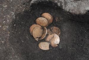 穴の中に土師器の皿が納められている様子